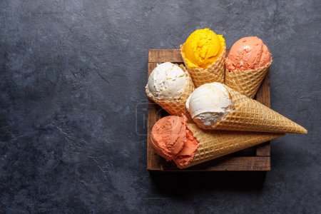 Téléchargez les photos : Saveurs variées de crème glacée dans de délicieux cônes de gaufres, un régal pour tous les papilles. Sur fond de pierre avec espace de copie. Pose plate - en image libre de droit