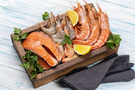 Photo for A top view of fresh seafood such as shrimp, langoustines, and trout steaks in wooden box - Royalty Free Image
