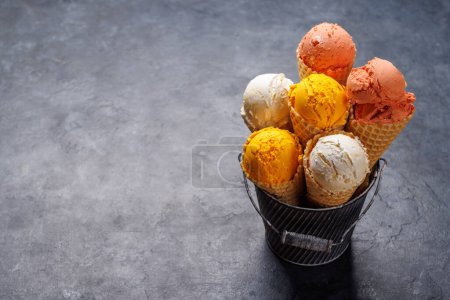 Foto de Surtido de sabores de helado en deliciosos conos de gofres, un regalo para todos los papilas gustativas. Sobre fondo de piedra con espacio de copia - Imagen libre de derechos