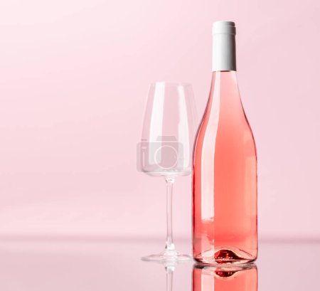 Téléchargez les photos : Bouteille de vin rose et verre de vin sur fond rose. Avec espace de copie - en image libre de droit