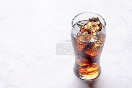 Téléchargez les photos : Verre rafraîchissant de cola avec glace. Sur table en pierre avec espace de copie - en image libre de droit