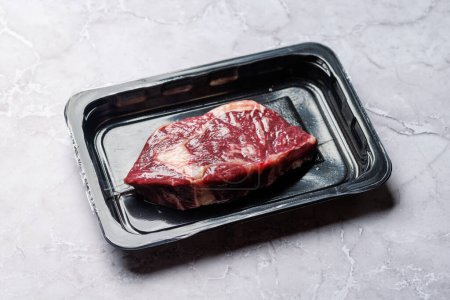 Téléchargez les photos : Bifteck de côtelette de bœuf cru frais scellé dans un emballage sous vide, préservant sa qualité et sa fraîcheur - en image libre de droit