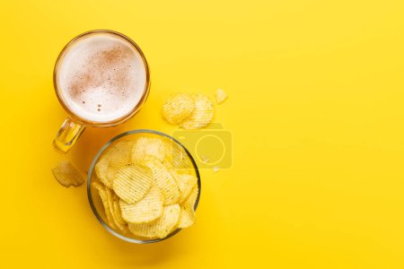 Photo for A tempting snack of beer and chips on a vibrant yellow background with copy space. Flat lay - Royalty Free Image
