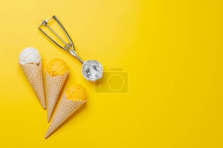 Téléchargez les photos : Saveurs variées de crème glacée dans de délicieux cônes de gaufres, un régal pour tous les papilles. Sur fond jaune avec espace de copie, pose plate - en image libre de droit