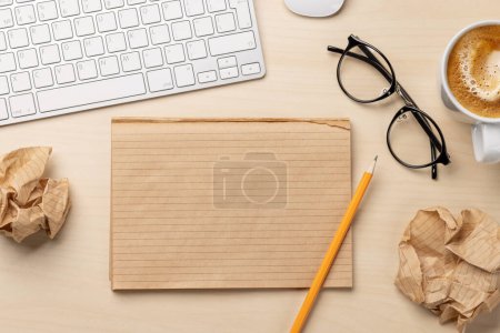 Photo for Top view of blank notepad, keyboard, coffee and crumpled papers on desk, depicting unsuccessful attempts at writing - Royalty Free Image