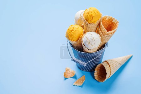 Photo for Lemon ice cream in delightful waffle cones, a treat for every taste bud. Over blue background with copy space - Royalty Free Image