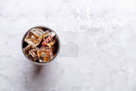 Téléchargez les photos : Verre rafraîchissant de cola avec glace. Sur table en pierre avec espace de copie. Pose plate - en image libre de droit