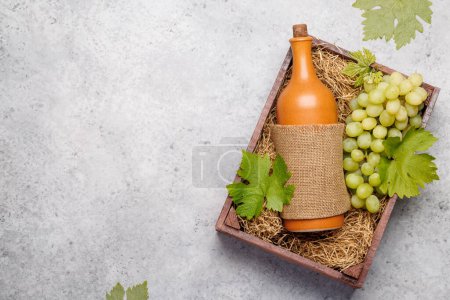 Téléchargez les photos : Une bouteille de vin rouge et des raisins frais, présentés dans une boîte en bois rustique. Pose plate avec espace de copie - en image libre de droit