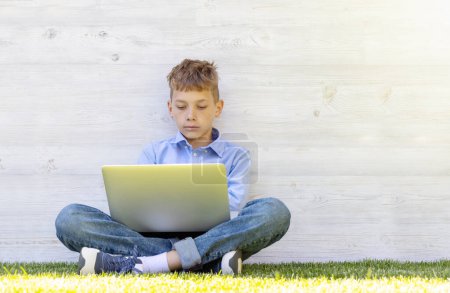 Photo for A boy using a laptop outdoors. Education or entertainment concept - Royalty Free Image