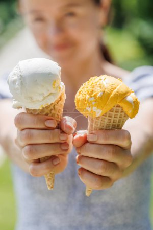 Photo for Woman's hands holding refreshing ice cream in waffle cones treats with a hint of zesty lemon flavour - Royalty Free Image