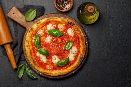 Téléchargez les photos : Pizza margarita maison, garnie de tomates fraîches, de fromage mozzarella et de feuilles de basilic aromatiques. Pose plate avec espace de copie - en image libre de droit