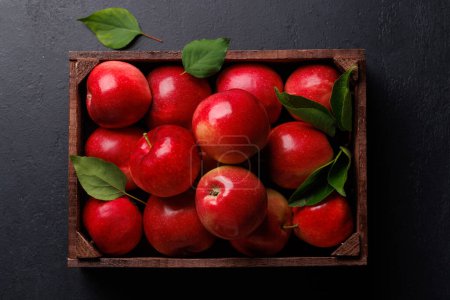 Photo for Wooden box with fresh red apples on stone table. Flat lay - Royalty Free Image