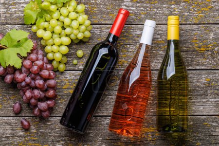 Foto de Botellas de vino y uva sobre mesa de madera. Puesta plana - Imagen libre de derechos