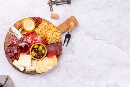 Photo for Antipasto board with prosciutto, salami, crackers, cheese, olives and nuts. Flat lay with copy space - Royalty Free Image