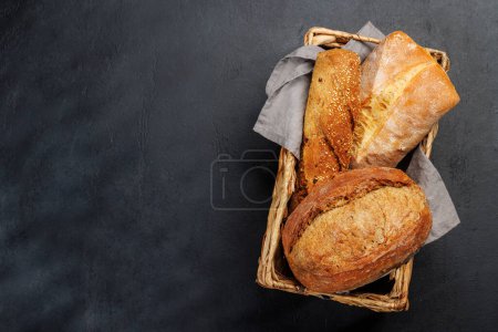 Téléchargez les photos : Variétés de pain variées dans un charmant panier, prêt à être dégusté. Pose plate avec espace de copie - en image libre de droit