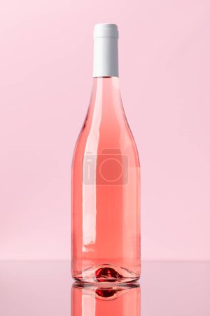 Photo for Rose wine bottle over rose background - Royalty Free Image