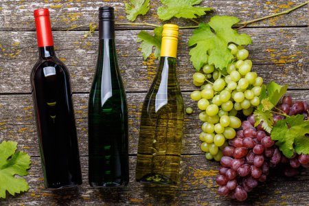 Foto de Botellas de vino y uva sobre mesa de madera. Puesta plana - Imagen libre de derechos