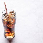 Refreshing glass of cola with ice. On stone table with copy space