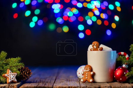 Foto de Chocolate caliente con malvavisco, galletas de jengibre, rama de árbol de Navidad con decoración y guirnalda bokeh - Imagen libre de derechos