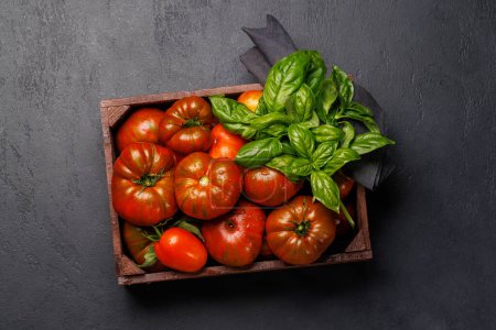 Foto de Tomates surtidos en cajón rústico y albahaca de jardín fresco. Puesta plana - Imagen libre de derechos