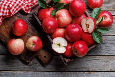 Wooden box with fresh red apples on wood table. Flat lay
