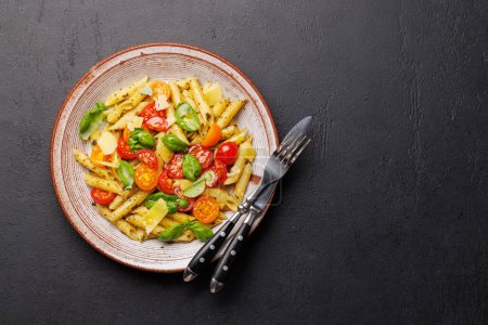 Foto de Un delicioso plato de pasta italiana adornada con tomates frescos y hojas aromáticas de albahaca. Piso con espacio de copia - Imagen libre de derechos