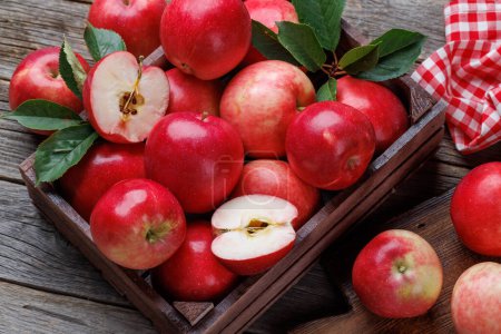 Foto de Caja de madera con manzanas rojas frescas en la mesa de madera - Imagen libre de derechos