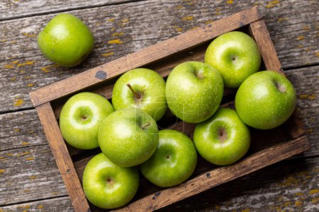Photo for Wooden box with fresh green apples on wood table. Flat lay - Royalty Free Image