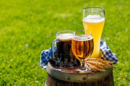 Photo for Variety of beer glasses on rustic wooden barrel. Sunny outdoor with copy space - Royalty Free Image