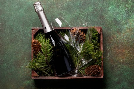 Foto de Caja de Navidad con ramas de abeto y champán. Piso con espacio para tus saludos de Navidad - Imagen libre de derechos