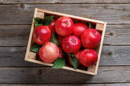 Photo for Wooden box with fresh red apples on wood table. Flat lay - Royalty Free Image