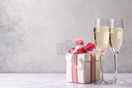 Foto de Dos copas de champán y una caja de regalo. Tarjeta de felicitación de Navidad plantilla con espacio de copia - Imagen libre de derechos