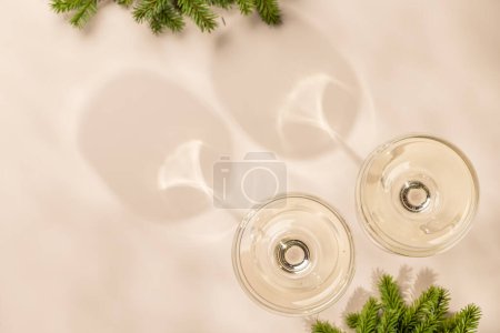 Téléchargez les photos : Deux verres à champagne sur fond beige avec espace de copie. Modèle de carte de voeux de Noël - en image libre de droit