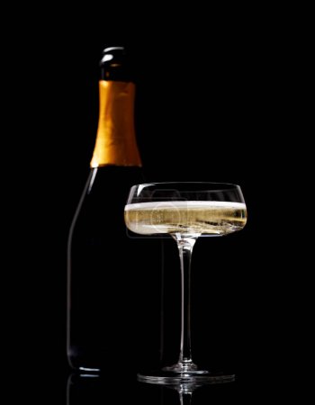 Foto de Copa y botella de champán sobre fondo negro - Imagen libre de derechos