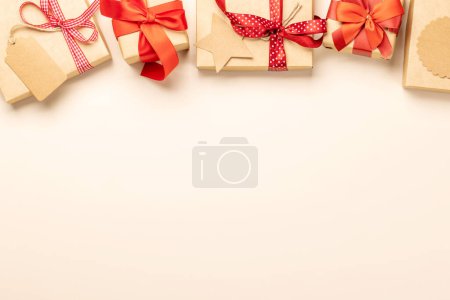 Photo for Christmas gift boxes over beige backdrop and space for greetings text. Flat lay - Royalty Free Image