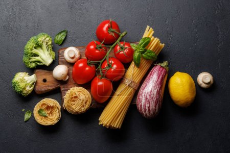 Téléchargez les photos : Variété de légumes et de pâtes. Pose plate sur fond de pierre sombre avec espace de copie - en image libre de droit
