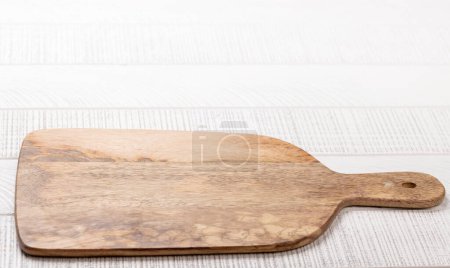 Téléchargez les photos : Planche à découper en bois sur table de cuisine blanche. Avec espace de copie - en image libre de droit