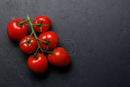 Photo for Vibrant tomato branch with ripe, juicy fruits. Flay lay on stone table with copy space - Royalty Free Image