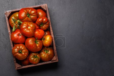 Foto de Tomates surtidos en cajón rústico. Piso puesto en la mesa de piedra con espacio de copia - Imagen libre de derechos