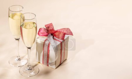 Foto de Dos copas de champán y una caja de regalo. Tarjeta de felicitación de Navidad plantilla con espacio de copia - Imagen libre de derechos