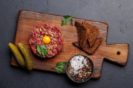 Foto de Tartare de carne salada con pepinillos en escabeche y tostadas de pan marrón. Puesta plana - Imagen libre de derechos