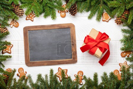 Téléchargez les photos : Branche de sapin de Noël avec décor, biscuits, boîte cadeau et tableau pour le texte de salutations. Pose plate - en image libre de droit