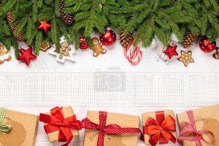 Photo for Christmas fir tree branch with decor, cookies, gift boxes and space for greetings text. Flat lay - Royalty Free Image
