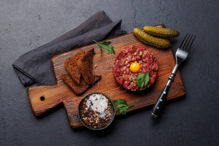 Téléchargez les photos : Tartare de bœuf salé avec cornichons marinés et pain grillé brun. Pose plate - en image libre de droit