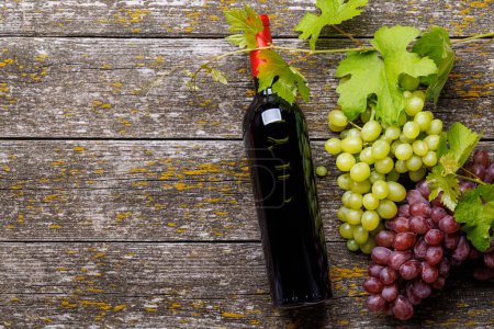 Téléchargez les photos : Bouteille de vin et raisin sur table en bois. Pose plate avec espace de copie - en image libre de droit