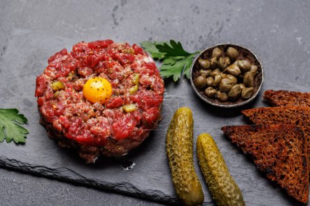 Photo for Savory beef tartare with pickled gherkins and brown bread toasts - Royalty Free Image