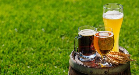 Photo for Variety of beer glasses on rustic wooden barrel. Sunny outdoor with copy space - Royalty Free Image
