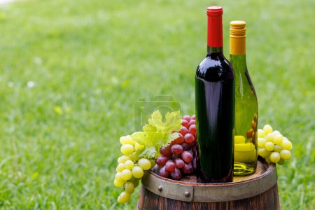 Photo for Wine bottles and grape on barrel outdoors with copy space - Royalty Free Image
