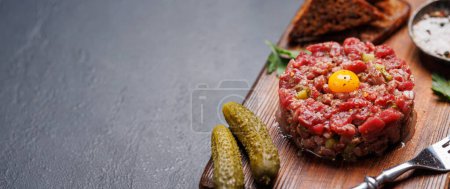 Téléchargez les photos : Tartare de bœuf salé avec cornichons marinés et pain grillé brun. Avec espace de copie - en image libre de droit