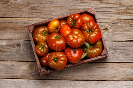 Téléchargez les photos : Tomates assorties dans une caisse rustique. Poser à plat sur une table en bois - en image libre de droit